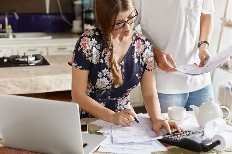 Pareja revisando facturas del hogar con una calculadora