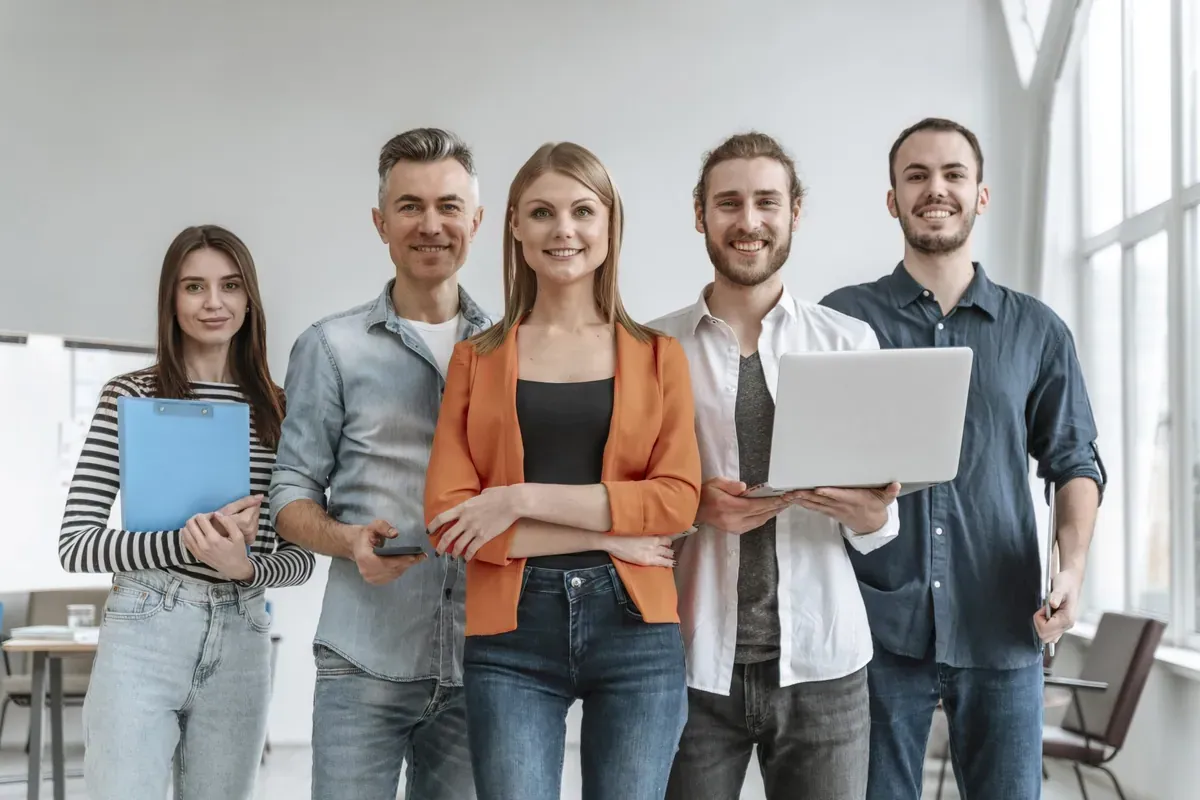 Equipo de cinco personas en una oficina con portátil, tableta y planilla