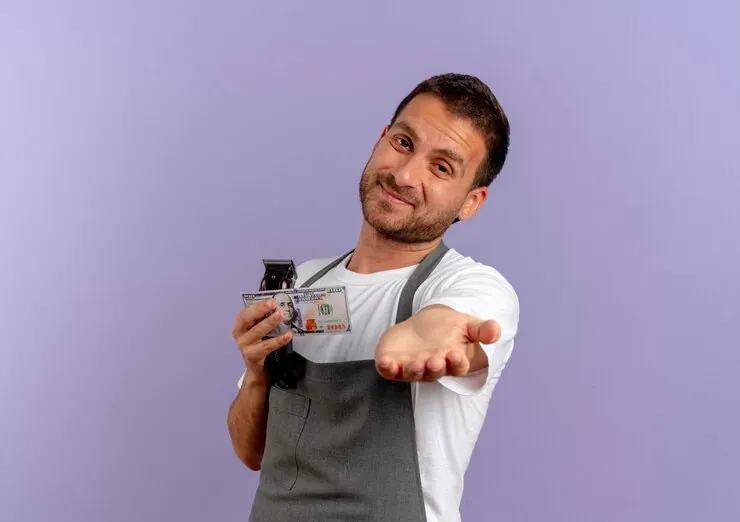 Trabajador con delantal sosteniendo un billete y extendiendo la mano